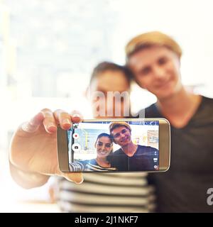 Study time selfies. Shot of two college students posing for a selfie together in a cafe. Stock Photo