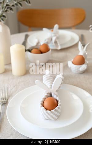 Easter table setting with egg in Easter bunny napkin on plate. Easter table serving. Stock Photo