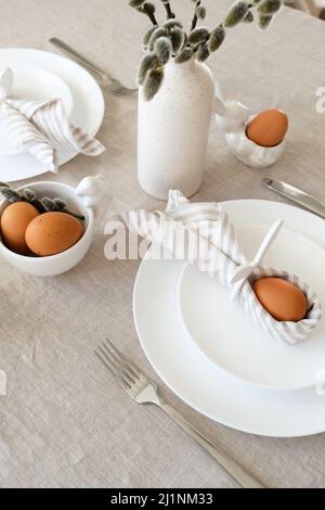 Easter still life. Easter dining table setting with Easter egg in bunny napkin and cutlery. Stock Photo