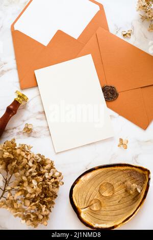 Autumn flat lay composition with wedding stationery, wedding invitation card mockup, golden rings, envelopes, dried flowers on marble table Stock Photo