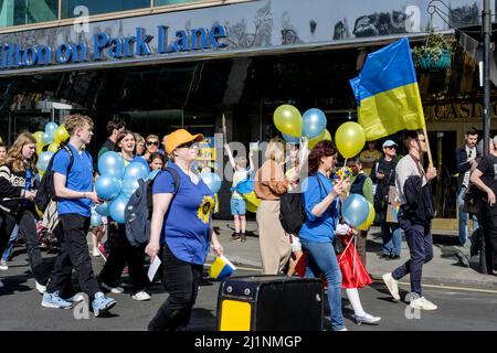 London UK, 26th March 2022. Thousands of people join a Stand with Ukraine march  and vigil in central London in protest against the Russian invasion. A group of young protesters pass the London Hilton on Park Lane hotel at the start of the march. Stock Photo