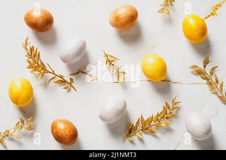 Bronze Easter eggs and golden branches on marble desk table. Top view. Stock Photo