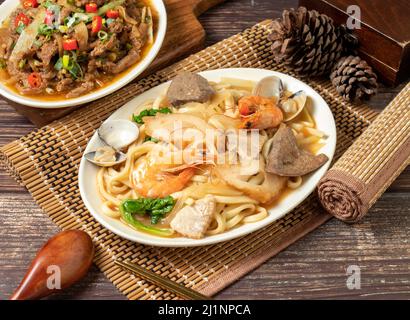 assorted fried noodles in a dish isolated on mat side view on dark wooden table taiwan food Stock Photo