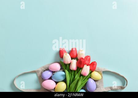A beautiful bouquet of tulips with a string bag containing painted eggs. Stock Photo