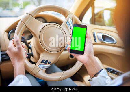 Checking her route. Shot of an unrecognizable businesswoman using her cellphone while driving to work on her morning commute. Stock Photo