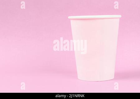 Pink disposable paper cups on pink background with empty space. Stock Photo