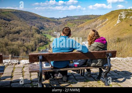 A couple of walkers sit on a bench at Monsal Head overlooking Monsal Dale to read a map. Stock Photo