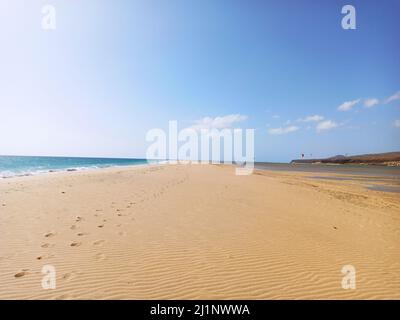 The sandy beach of Playa de Sotavento with footprints under a blue cloudy sky on a sunny day Stock Photo