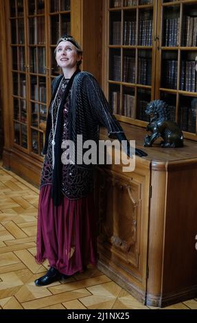 Sachsen, Germany. 27th Mar, 2022. Lara Klewin, an employee of the Kulturbetrieb Schloss Waldenburg, stands in the estate's library in 1920s costume. She embodies Eleonore von Schönburg-Waldenburg, who lived there at the beginning of the 20th century. For the event 'Enlivened Castle' was commemorated this time. Credit: Sebastian Willnow/dpa-Zentralbild/dpa/Alamy Live News