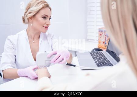 Focused doctor treating patient skin using laser device Stock Photo