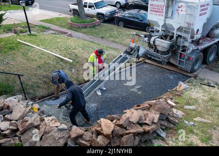 Workers pouring a new driveway at a home in Maryland USA  Concrete is laid over wire mesh and gravel to make the finished surface strong Stock Photo