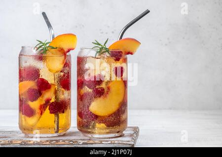 Peach lemonade with soda water and raspberries on grey table. Fresh summer cocktail Stock Photo