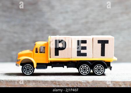 Truck hold letter block in word pet on wood background Stock Photo