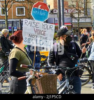 Braunschweig, Germany, March 25, 2022: Redhead woman and man in dark clothes with bicycle on demonstration for global climate strike 2022 Stock Photo