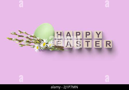 HAPPY EASTER on wooden cubes concept background with egg, willow and daisies Stock Photo