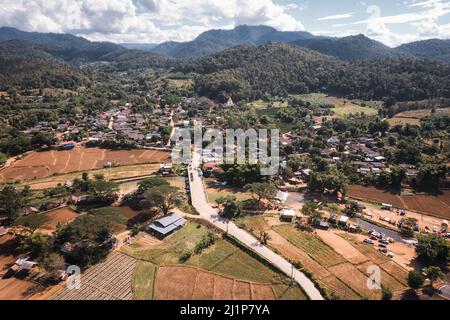 Aerial view of tranquil local village with river flowing through among the valley and rice plantation on dry season in countryside at Muang Kong, Chia