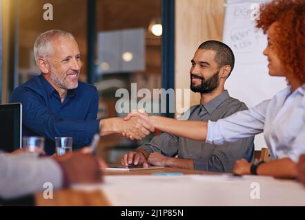 Collaborating to accomplish their goals. Shot of colleagues shaking hands in an office meeting. Stock Photo