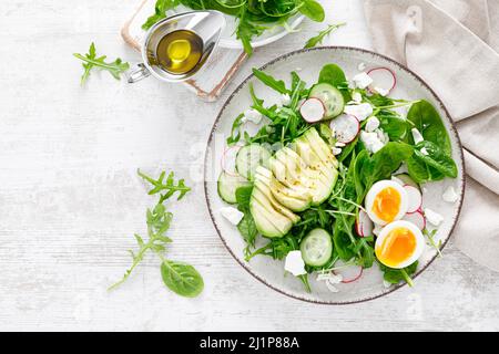 Avocado and boiled egg fresh vegetable salad with radish, cucumber, spinach, arugula and cottage cheese. Top view Stock Photo