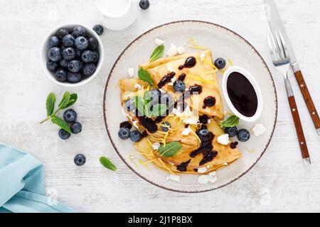 Crepes. Thin pancakes stuffed with cottage cheese and fresh blueberries. Top view Stock Photo