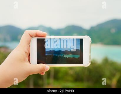 Just a slice of heaven on earth. Cropped shot of an unidentifiable person using a smartphone to photograph a tropical landscape. Stock Photo
