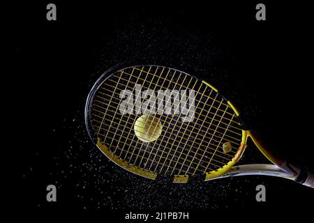 Tennis ball bouncing on racket. Dirt or magnesium dust dots visible in the air. Stock Photo