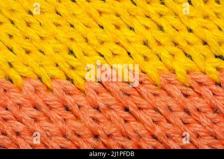 Yellow and red synthetic knitted fabric close up. Knitted fabric texture. Multicolor patterned knitted fabric texture. Background Stock Photo