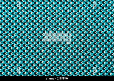 Synthetic knitted fabric with pattern elements of blue, black and white yarns close up. Multicolor patterned knitted fabric texture. Background Stock Photo