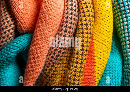 A pile of multi-colored synthetic knitted fabrics of different structures and textures. A stack of colorful fabrics smooth shapes background. Multicol Stock Photo