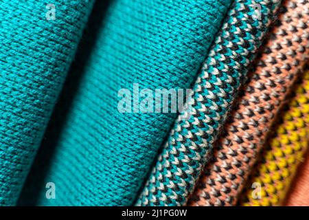 Stack of colorful knitted fabric, knitted winter clothes. Multicolored knitwear fabric background Stock Photo