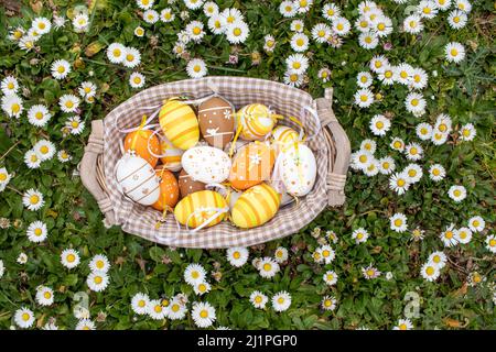 Happy Easter! Basket with decorated Easter eggs. Multicolored Easter eggs among daisies in the garden. Stock Photo
