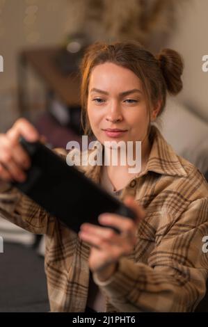 The girl carefully looks at the screen of a portable game console. Hobby, entertainment, virtual reality, cyberspace, new modern technologies, game st Stock Photo