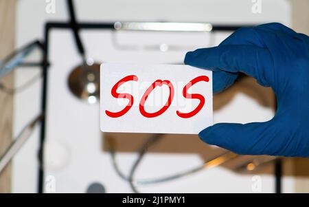 White lightbox with word SOS abbreviation of save our soul ship or sibling over shoulder on wood background. Stock Photo