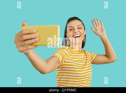 Happy woman taking selfie or making video call on phone, waving hello and smiling Stock Photo