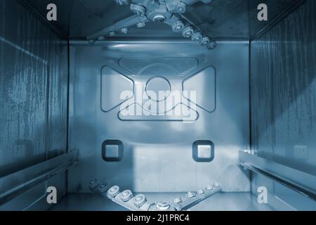 Close up photo of inside of metallic industrial dishwasher. Stock Photo