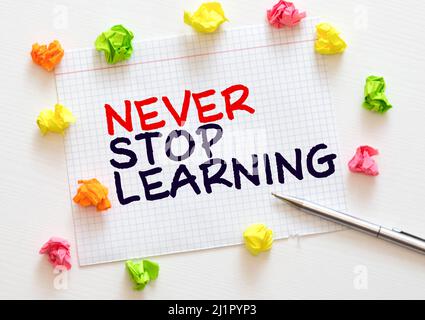 Never Stop Learning, handwriting quotation on notebook on white desk Stock Photo