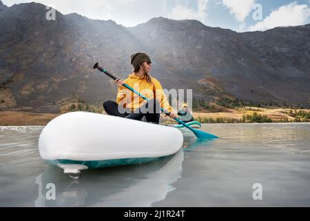 Two young girls walks on stand up paddle boards at mountain lake Stock Photo
