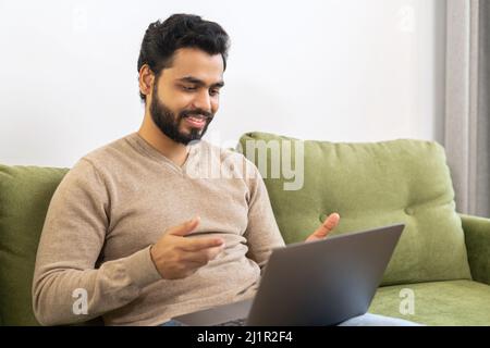 Focused middle eastern businessman holding video call with clients on laptop, concentrated man giving online educational class lecture, consulting customer Stock Photo