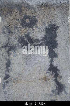 Old grey and black concrete wall with chipped pain and natural abstract design background texture Stock Photo