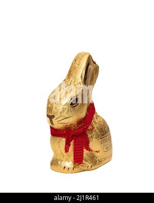 A milk chocolate Lindt Easter bunny wrapped in gold foil with a red ribbon necklace isolated on white Stock Photo