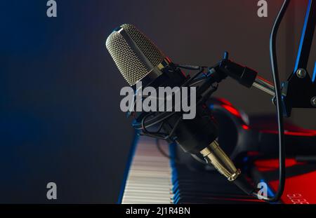 MIDI keyboard and microphone on a blue background. There are no people in the photo. Music, singing, concert, sound equipment, electronics, modern tec Stock Photo