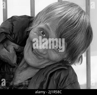 Old lady tramp smiling at camera whilst begging on the streets of Hong Kong. Stock Photo