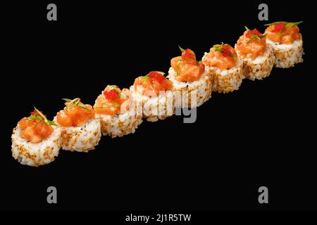 japanese sushi roll with salmon, Philadelphia cheese, green onion, tobiko caviar, Aroy-D sauce, sesame. isolated on black background Stock Photo