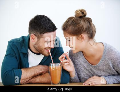 Stop sipping so fast. Shot of an attractive young couple sharing a milkshake together. Stock Photo