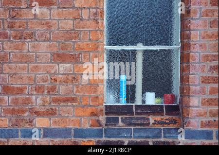 pattern background image of frosted window on old redbrick wall with line of black bricks Stock Photo