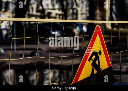 Roadworks, under construction. Earthwork sign on fence with trench hole in background, replace water pipes Stock Photo