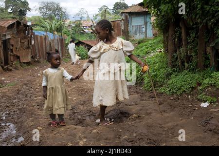 Sisters walking to school carrying a small dumpling, Majengo slum, Meru Stock Photo