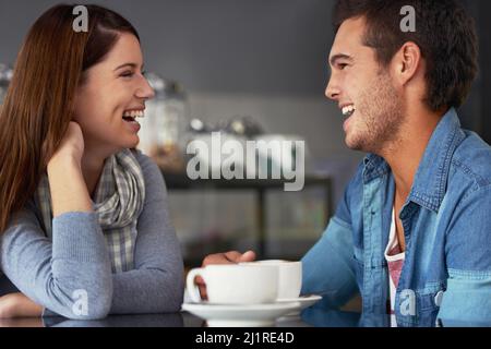 He always makes her smile. A loving young couple at a coffee shop together. Stock Photo