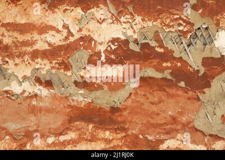 Authentic red gray background with pink tints. Wooden planks under weathered plaster of the dilapidated wall of the old house. Stock Photo