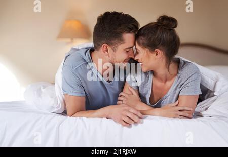 Were growing closer by the day. Shot of an affectionate young couple spending some quality time together in their bedroom at home. Stock Photo