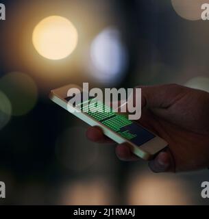 Hacking has never been easier. Shot of an unidentifiable computer hacker using a smartphone to hack into a network. Stock Photo